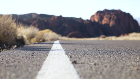 cyclist biking on asphalt road in moab, utah with scenic sandstone in background