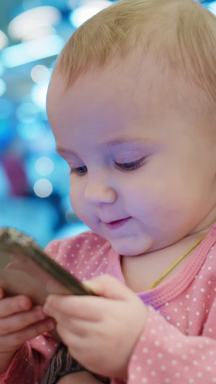 幼い子供がスマートフォンに夢中になっている様子。現代生活におけるテクノロジーやデジタルデバイスと触れ合う、幼児期の好奇心と集中力を捉えた一枚です。