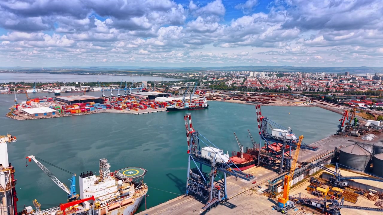 Burgas, Bulgaria, 10 April 2026: Aerial view of cargo port with containers and cranes, Burgas, Bulgaria. Drone perspective over turquoise harbor basin with cityscape under cloudy sky.