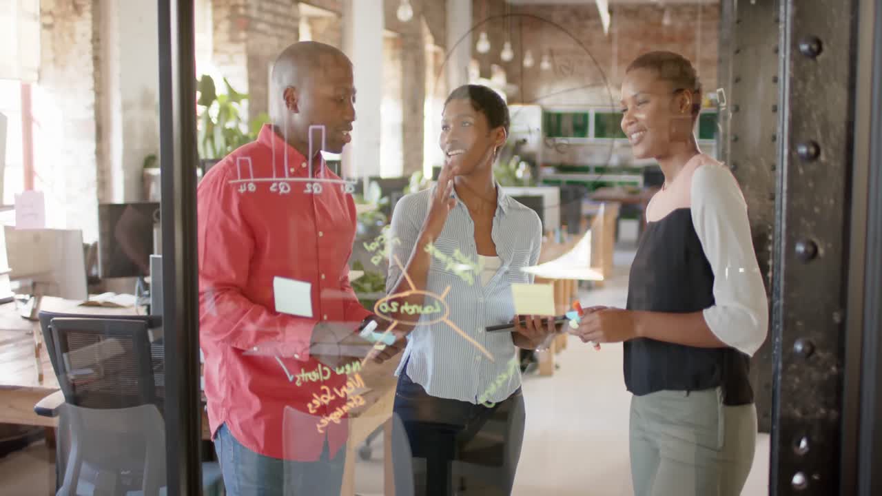 felices colegas afroamericanos tomando notas en la pared de vidrio y discutiendo el trabajo, cámara lenta