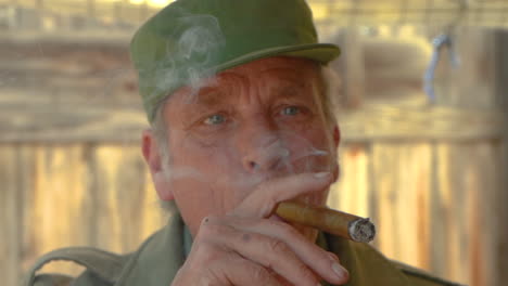 retrato de un hombre apuesto de unos 60 años, ojos azules, fumando un cigarro y asintiendo