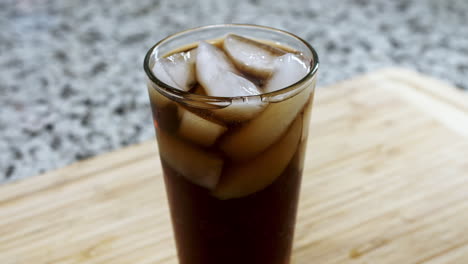 soda pop bubbles rising in a pint glass set on a wood cutting board