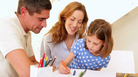 padres e hija coloreando juntos en la mesa