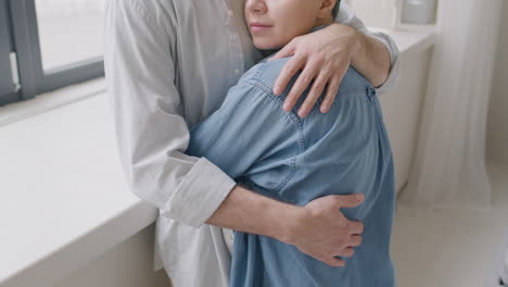 young woman with closed eyes hugging her boyfriend at home