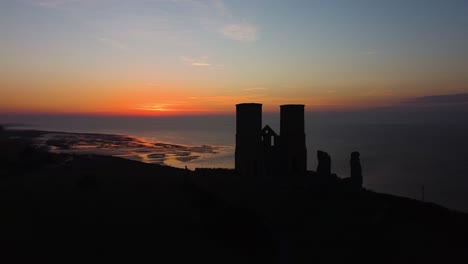 silhouette of reculver towers against orange sunset skies