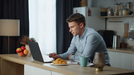 Man-talking-zoom-meeting-sitting-at-home-kitchen.-Guy-working-remotely-at-home.