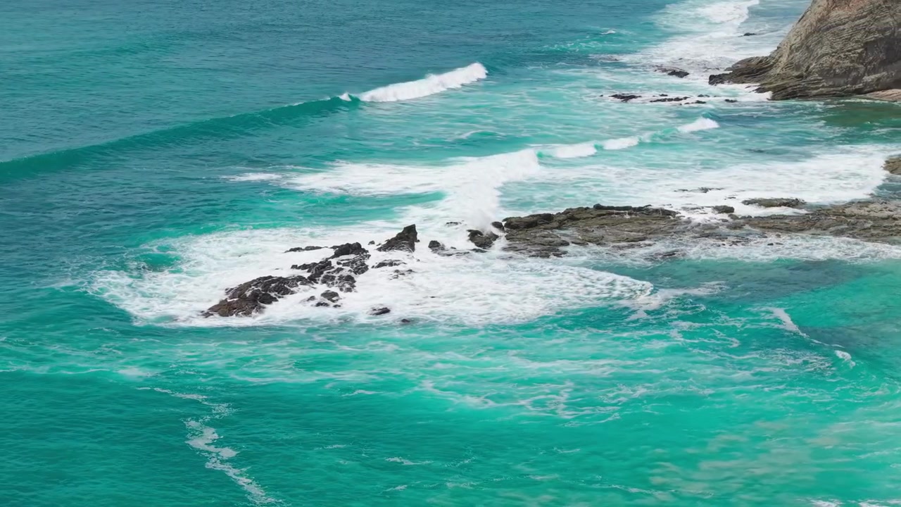 Vista aerea con panoramica a sinistra di onde che si infrangono su scogliere rocciose lungo la costa tropicale di Playa Barrigona in Costa Rica.