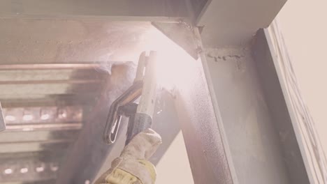 sparks fly as welder wearing safety gloves weld steel structure