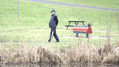 locked-off tracking view, elderly gentleman strolling through local park