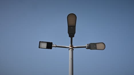 4k: led streetlight on the high metal pole under the clear blue sky, modern electric led street light pole, low angle shot