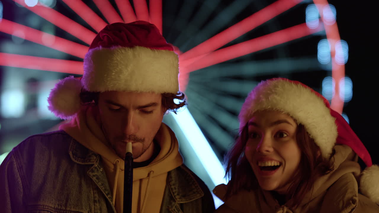 야외에서 축제용 파이프를 불고 있는 즐거운 커플. 도시 거리에서 키스하는 행복한 쌍.