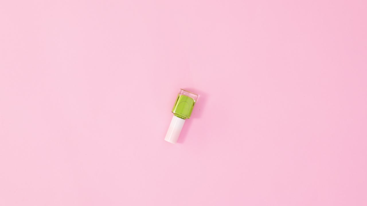 botella de esmalte de uñas de manicura girando sobre un fondo rosa pastel. colocación plana de movimiento de parada