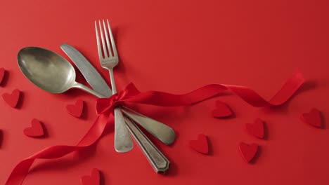 Red-ribbon-and-cutlery-with-hearts-on-red-background-at-valentine's-day