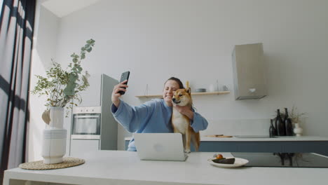 beautiful young woman takes a selfie with her dog at home