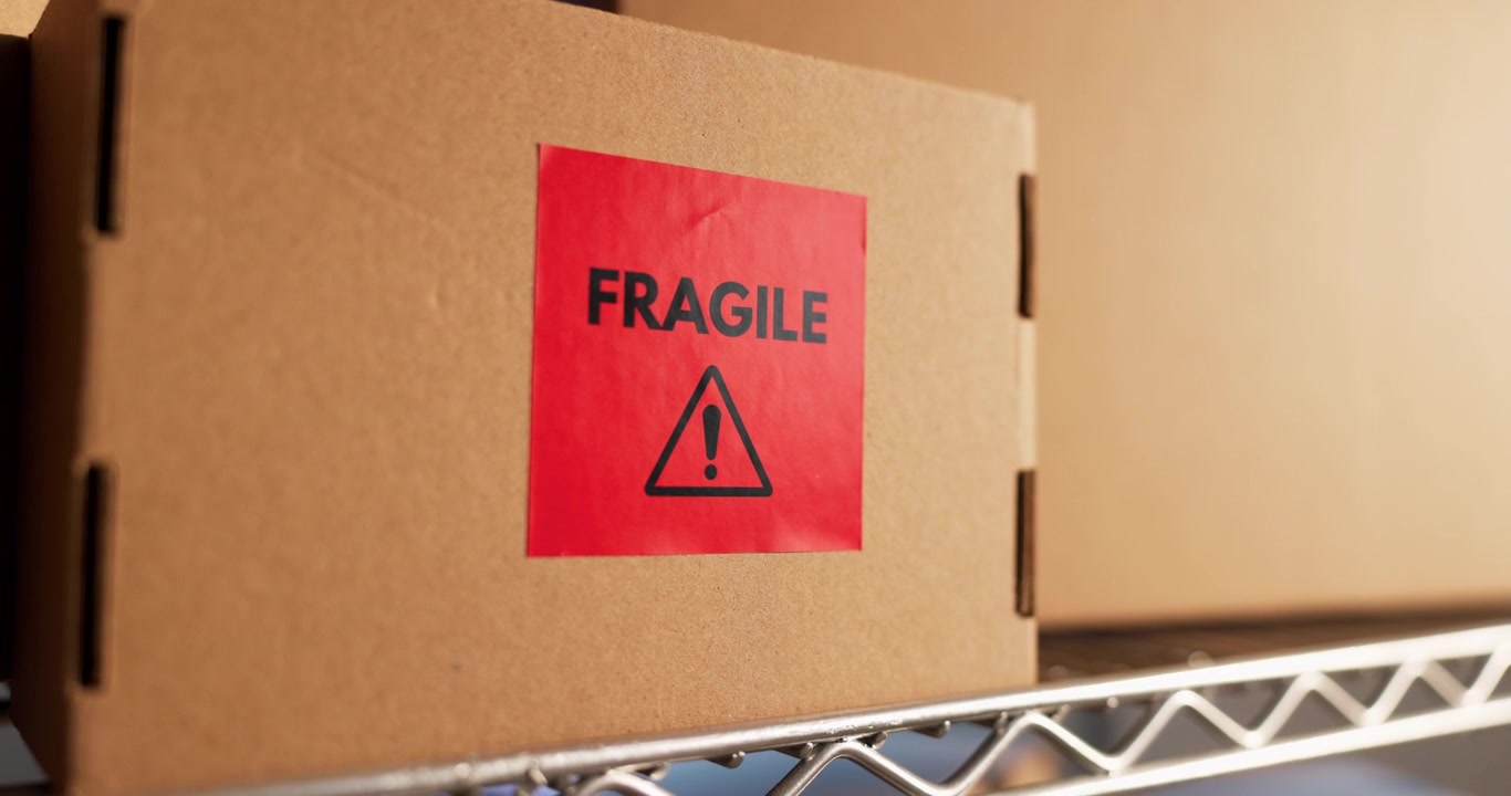 Caixa de papelão com etiqueta de aviso de frágil em prateleira de metal
