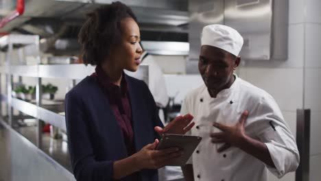 African-american-female-manager-using-tablet-and-talking-with-chef