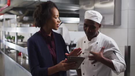 gerente femenina afroamericana usando una tableta y hablando con el chef
