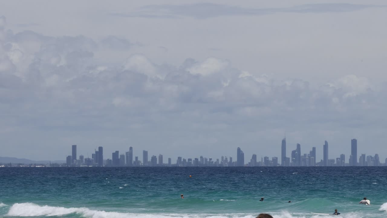 도시 스카이라인을 배경으로 파도를 즐기는 서퍼들