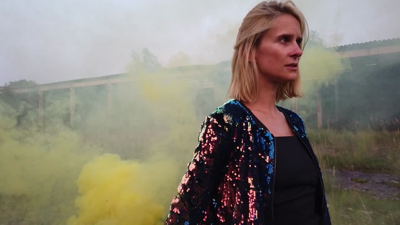 Gorgeous slow motion cinematic shot of a pretty young girl in sparkly bomber jacket yellow smokeColorful fog shooting Russians airplane hangar. Shot lost places in nature 1080, 24p by Philipp Marnitz