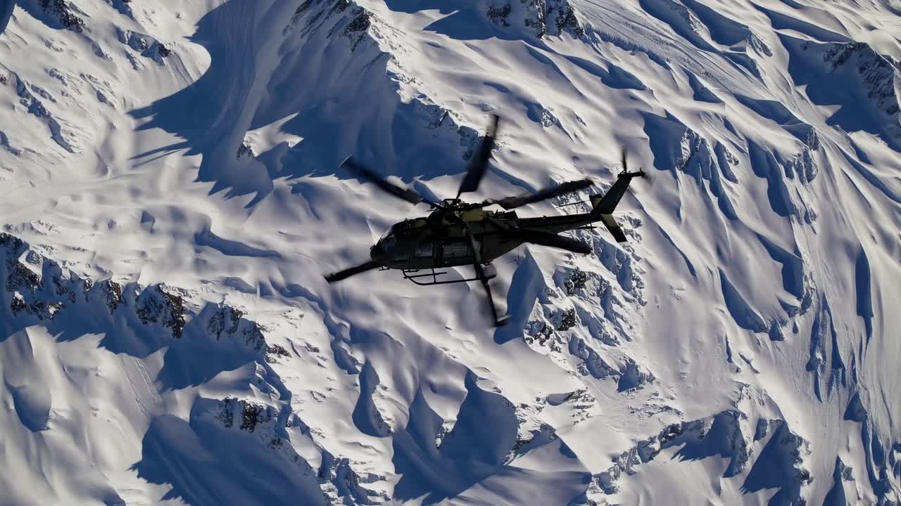 Aerial video of a helicopter flying over snow-covered mountains