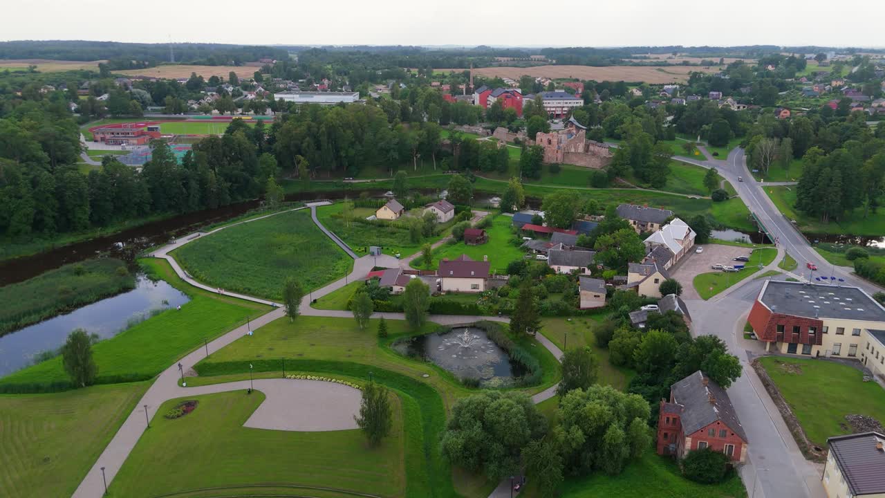 Aerial View of Dobele Castle Ruins, Flowing Berze River and Illuminated Fountains at Sunset Serene Latvian Summer Evening from Above, Scenic Aerial of Latvian Historical Landscape in Golden Hour