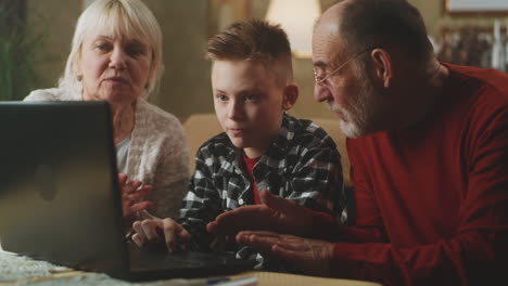 grandparents and grandchild looking at a laptop