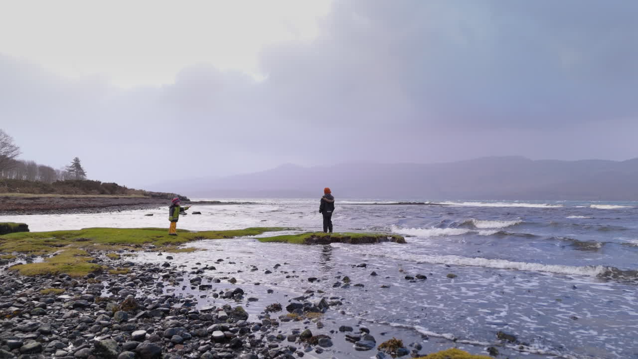 Boy and girl siblings explore cobble coastline of Scotland West Coast, gimbal