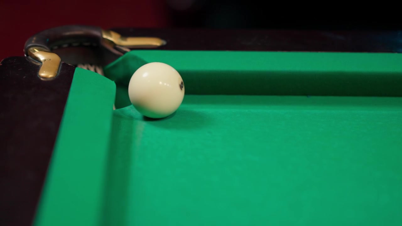 Primer plano de la bola blanca golpeando otra bola en una mesa de billar verde.