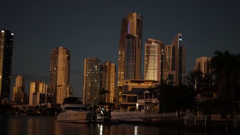 skyscrapers and boats along a canal at night