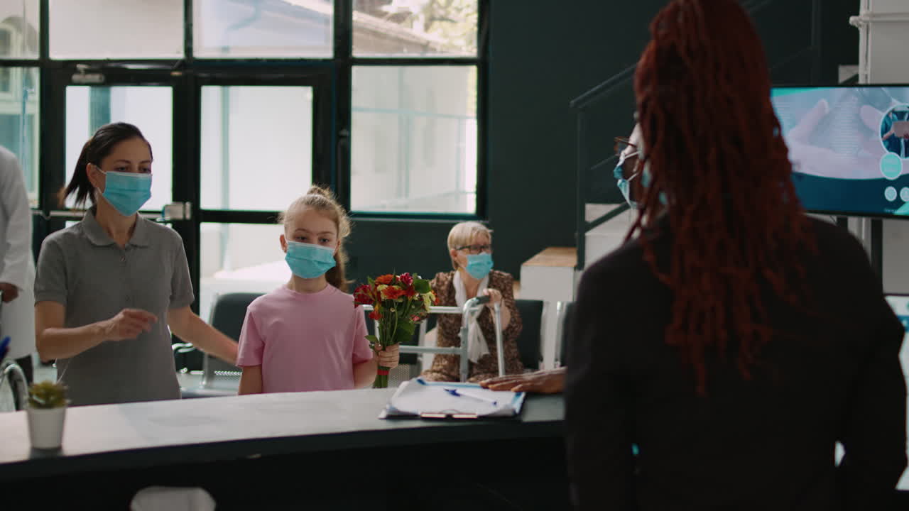 Woman and little girl with facemask talking to receptionist
