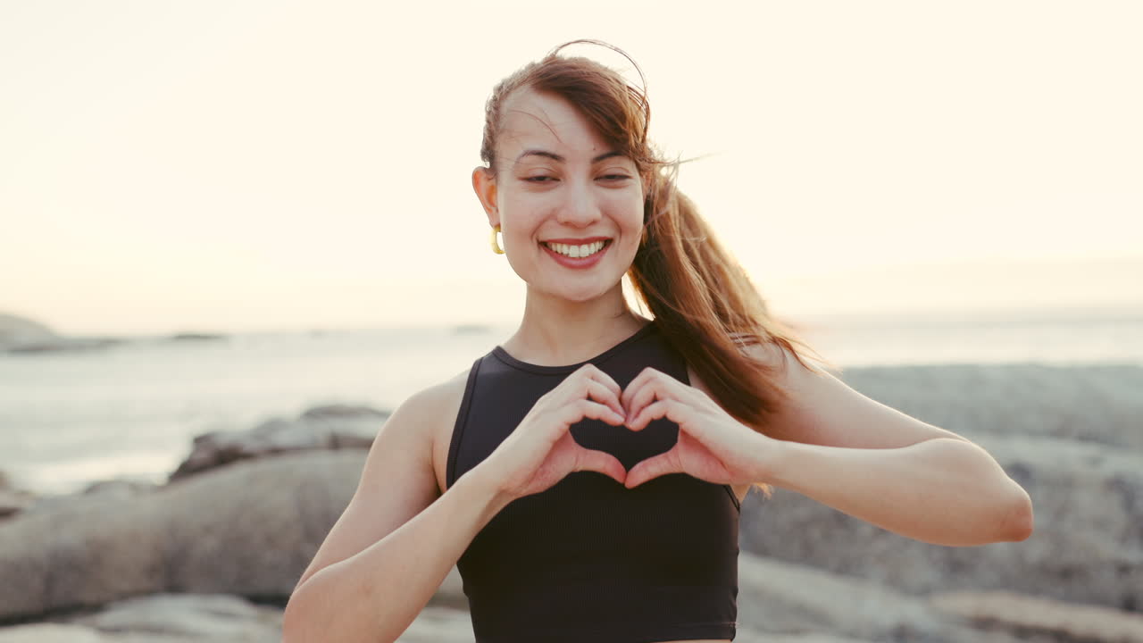 해변 피트니스에서 심장 손을 가진 여성의 얼굴