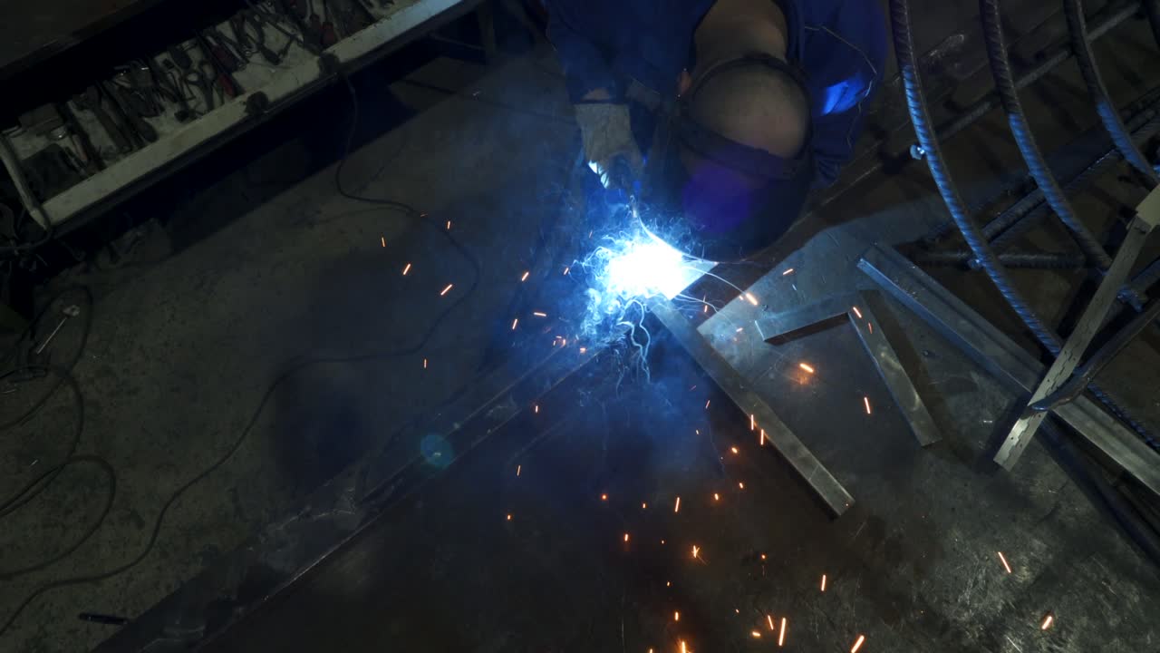 Anonymous workman welding metal construction in workshop