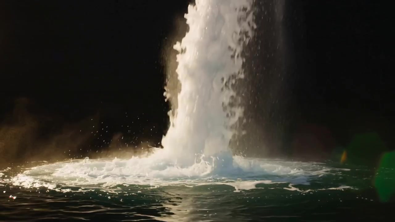 海底爆発後、沿岸のプールから噴出する高い水柱が泡立つ輪と霧を押し上げている