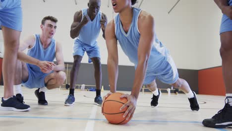 entrenamiento de un equipo de baloncesto masculino diverso, jugador motivador haciendo abdominales en la pelota, cámara lenta