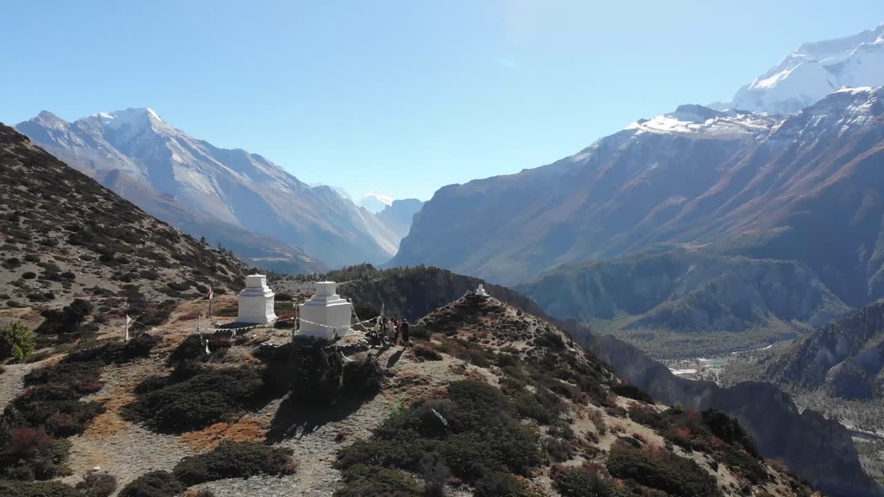 excursionistas junto a pequeños templos en el circuito de annapurna viendo la majestuosa cordillera de annapurna en nepal