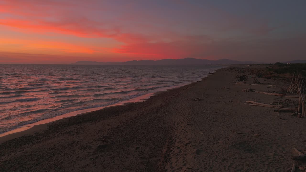 un tipo de madera a la deriva en una playa de arena al atardecer