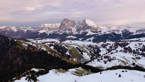 Vista-Aérea-Panorámica-Hacia-Atrás-De-La-Cordillera-De-Los-Dolomitas-Cubierta-De-Nieve-Desde-Seiser-Alm---Meseta-Alpe-Di-Siusi-En-Tirol-Del-Sur,-Italia-Alrededor-De-La-Puesta-Del-Sol