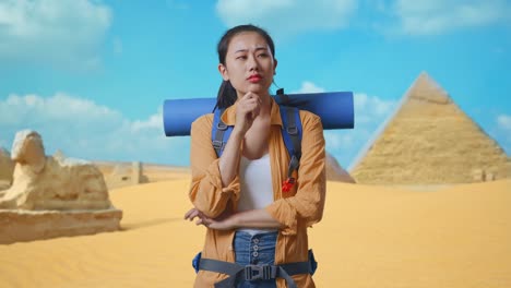 asian female hiker with mountaineering backpack thinking about something and looking around then raising her index finger while traveling in pyramid of giza