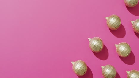 Video-of-rows-of-mirror-balls-and-shadows-on-pink-background-with-copy-space