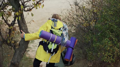 Couple-hikers-walk-in-forest-park-with-backpacks,-crawling-through-the-bushes