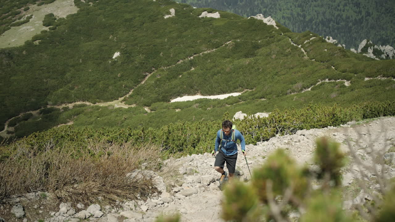 hombre caminando por un camino rocoso con bastones de senderismo en el fondo es un hermoso valle kárstico verde con caminos visibles fuera de la carretera