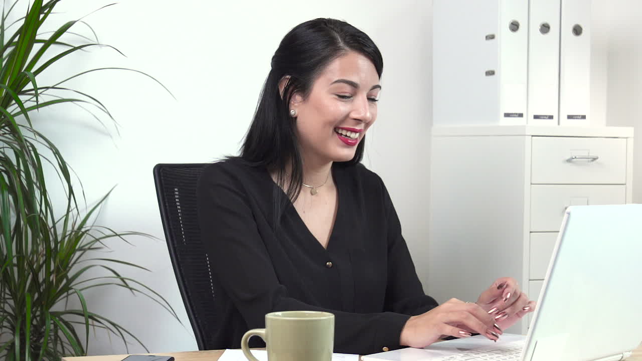 Empleada de oficina atractiva sonriendo al ordenador