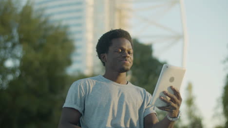 young guy in wheelchair having video chat on tablet outdoors