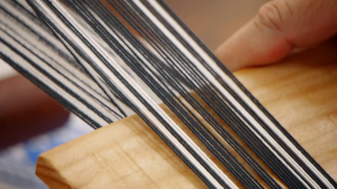 dedos enhebrando y presionando hilo blanco y negro