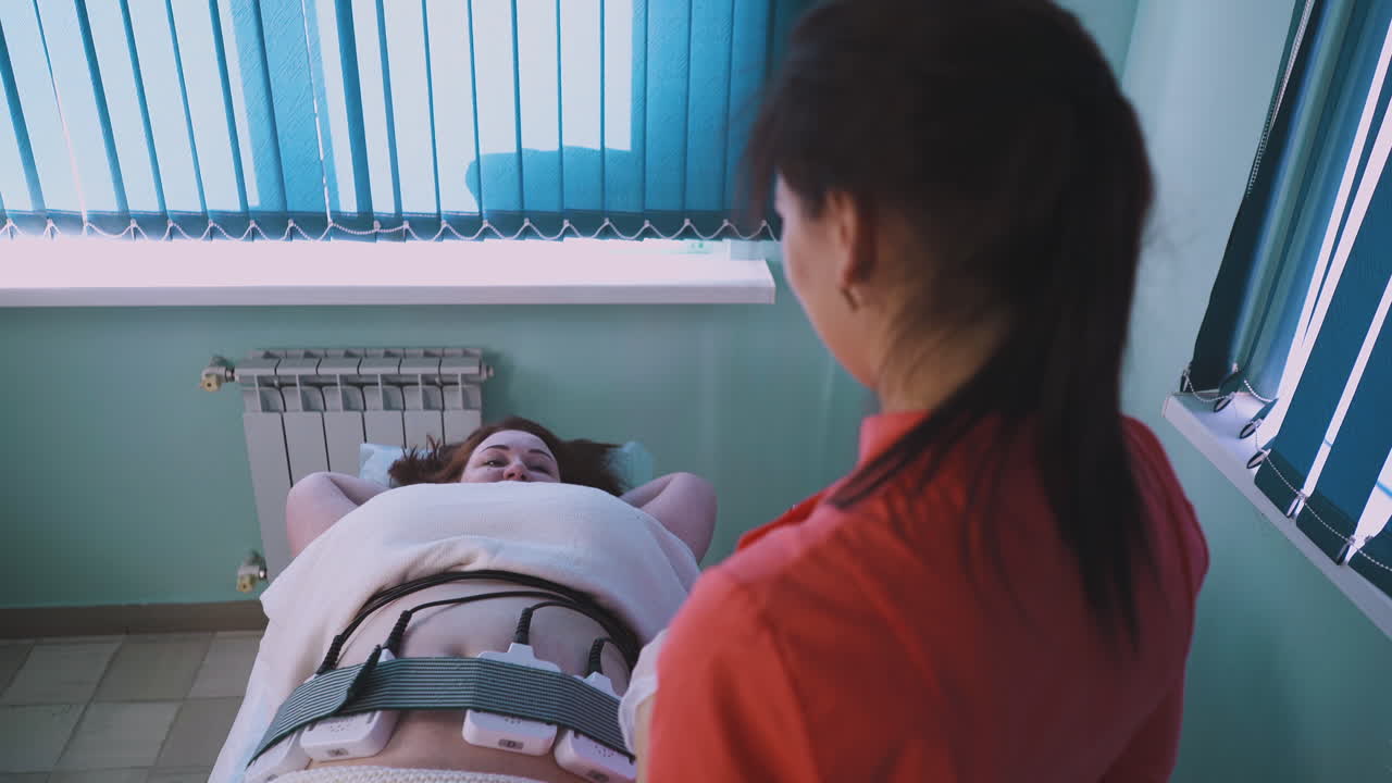 여성이 플러스 사이즈 클라이언트의 전기적 근육 자극을 제어합니다.