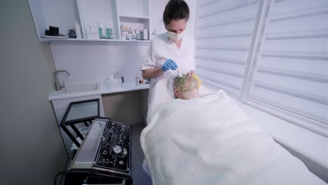 procedimientos profesionales de cuidado facial en la clínica de cosmetología moderna. aplicación de máscaras faciales