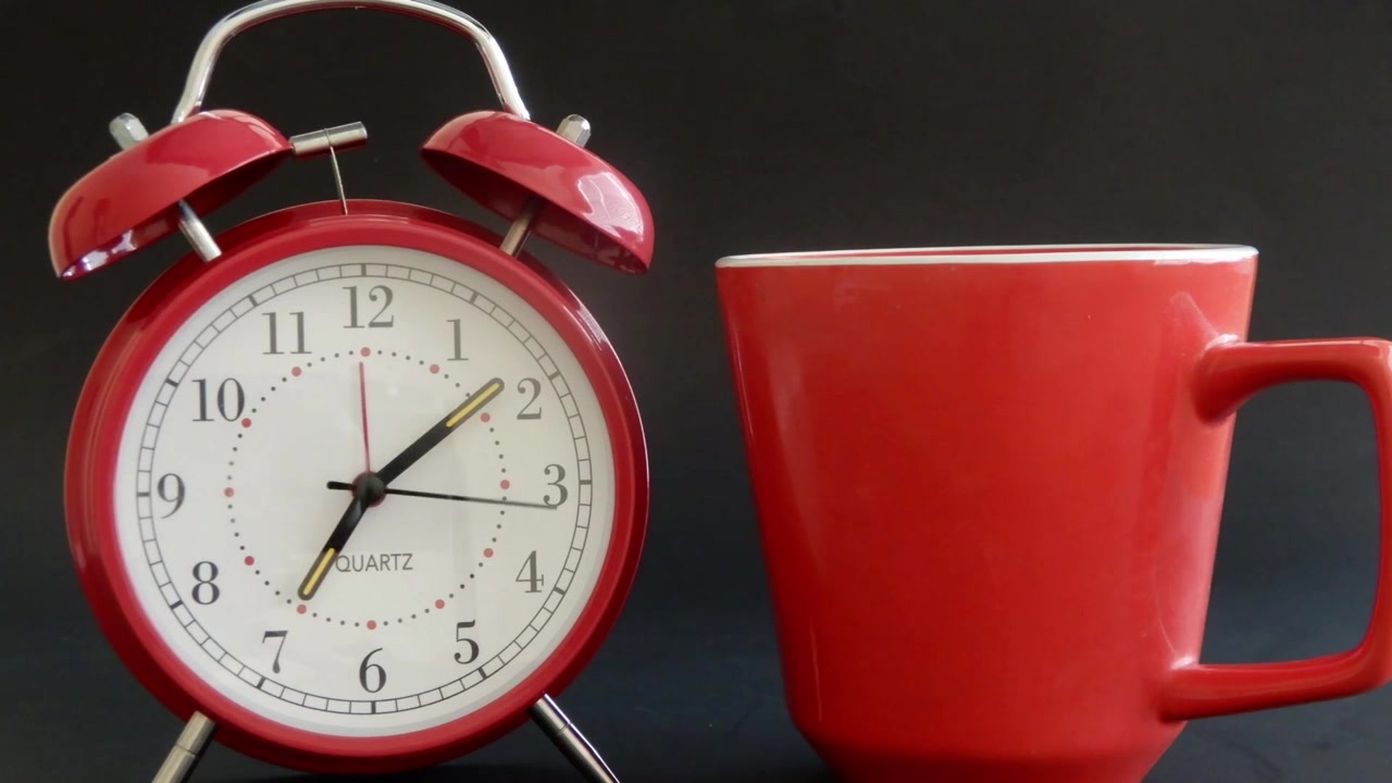 Tazza di caffè per iniziare la giornata e una sveglia in rapido movimento