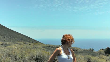 un plano medio alrededor de una mujer elegante pelirroja en una isla volcánica