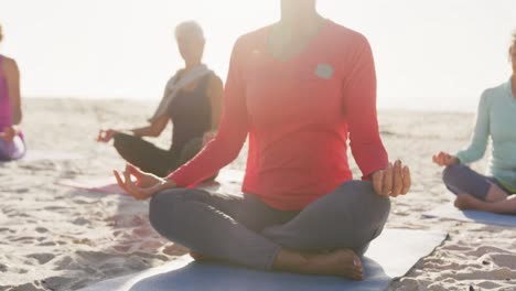 athletic women performing yoga in the beach