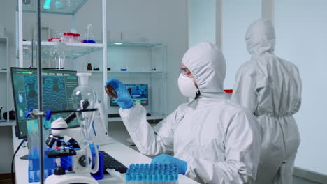 científico en traje ppe sosteniendo una placa de petri mientras estudia muestras de virus